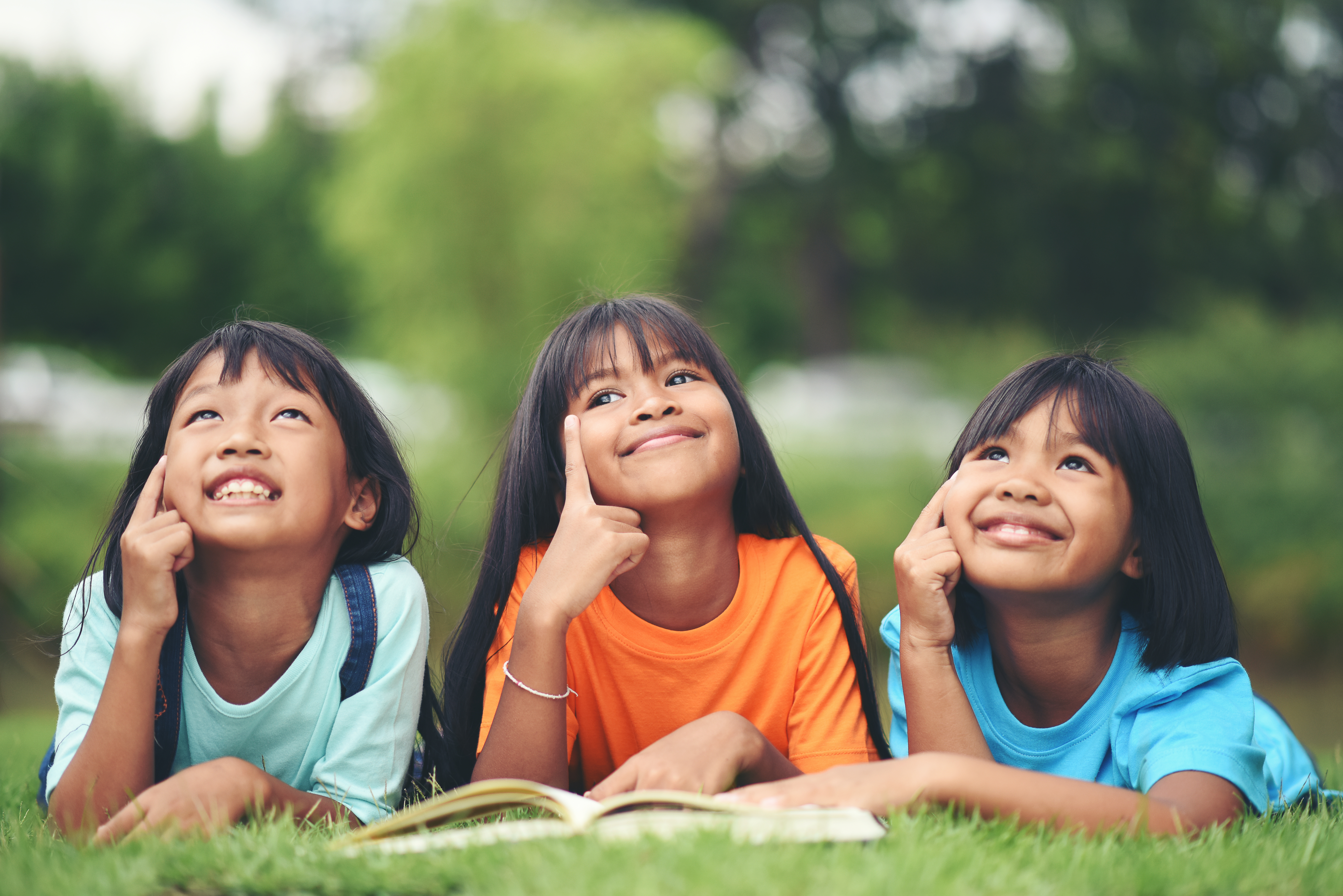 group of children lying reading on grass field